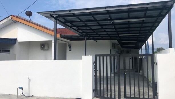 Una entrada protegida por una reja a un edificio con techo metálico y pared exterior blanca.
