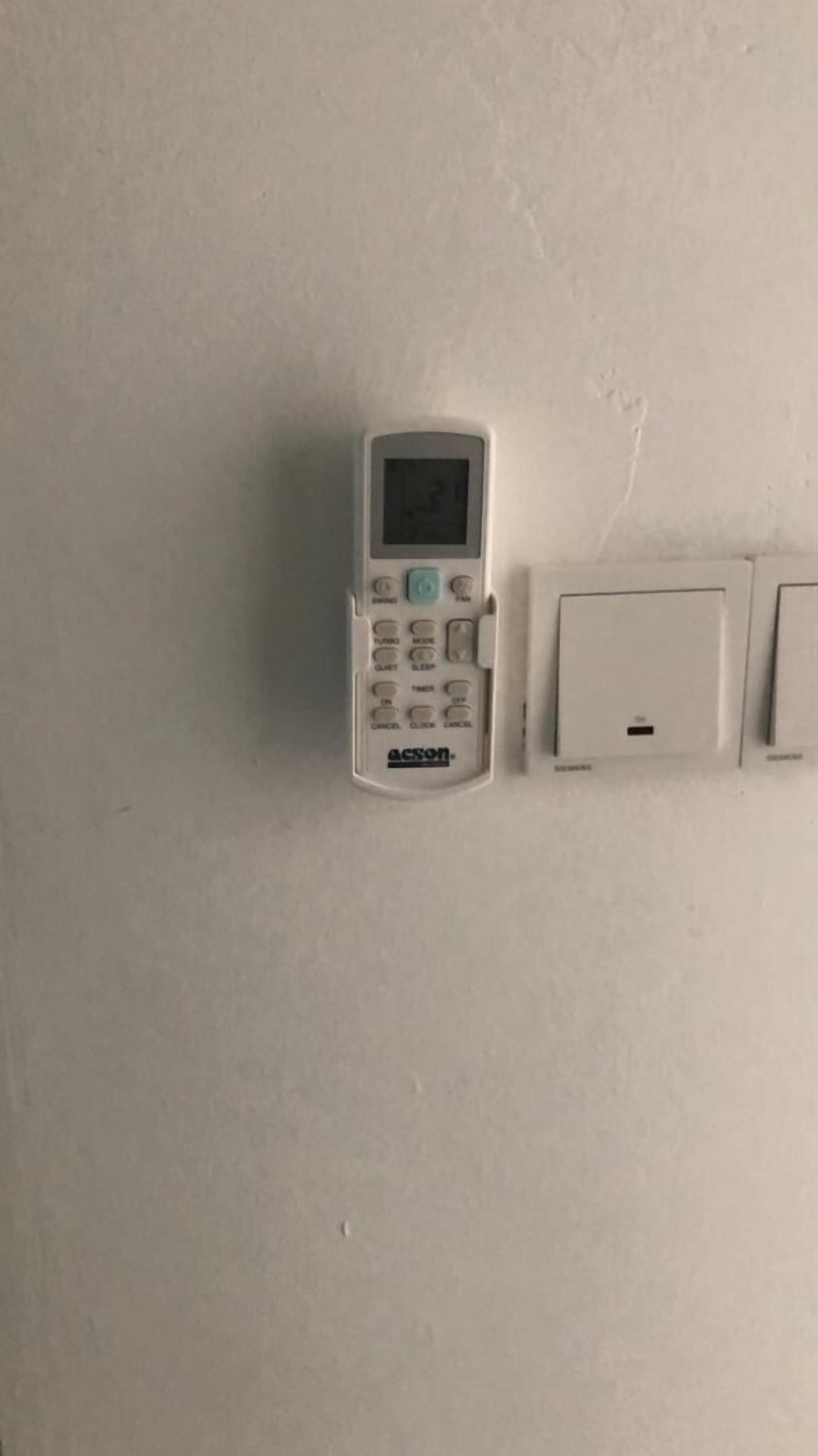 A white mobile phone and a wall-mounted intercom on a plain wall.