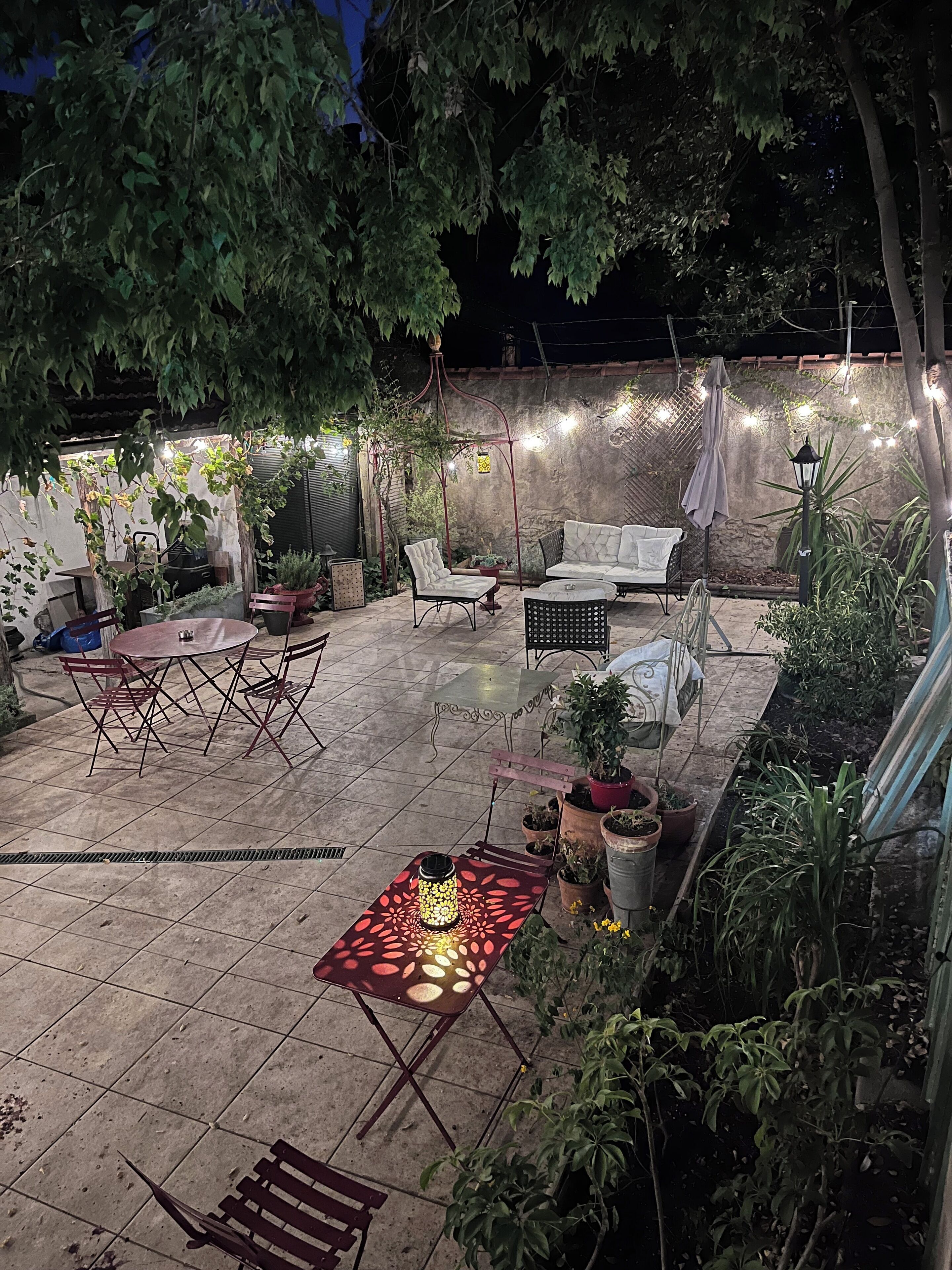 An outdoor patio area with a dining table, chairs, a sofa, and potted plants.