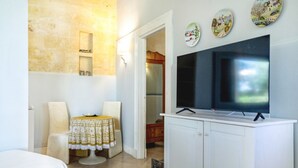 Ein Hotelzimmer mit einem Bett, einem Tisch mit Tischdecke, einem Fernseher auf einem Schrank und einer Steinwand.