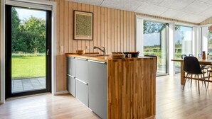 Une cuisine moderne avec un îlot central en bois, un évier et un coin repas comprenant une table et des chaises.