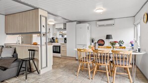 Een kleine keuken met een eethoek, met een inbouwoven, een koelkast en een eettafel met stoelen.