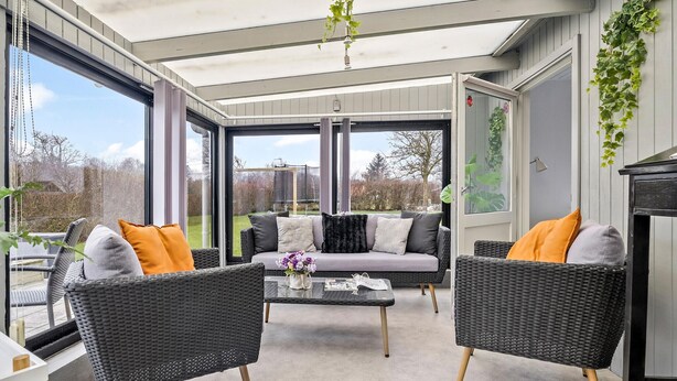 Een moderne buiten zithoek met rieten meubilair, een glazen bijzettafeltje en uitzicht op de tuin.