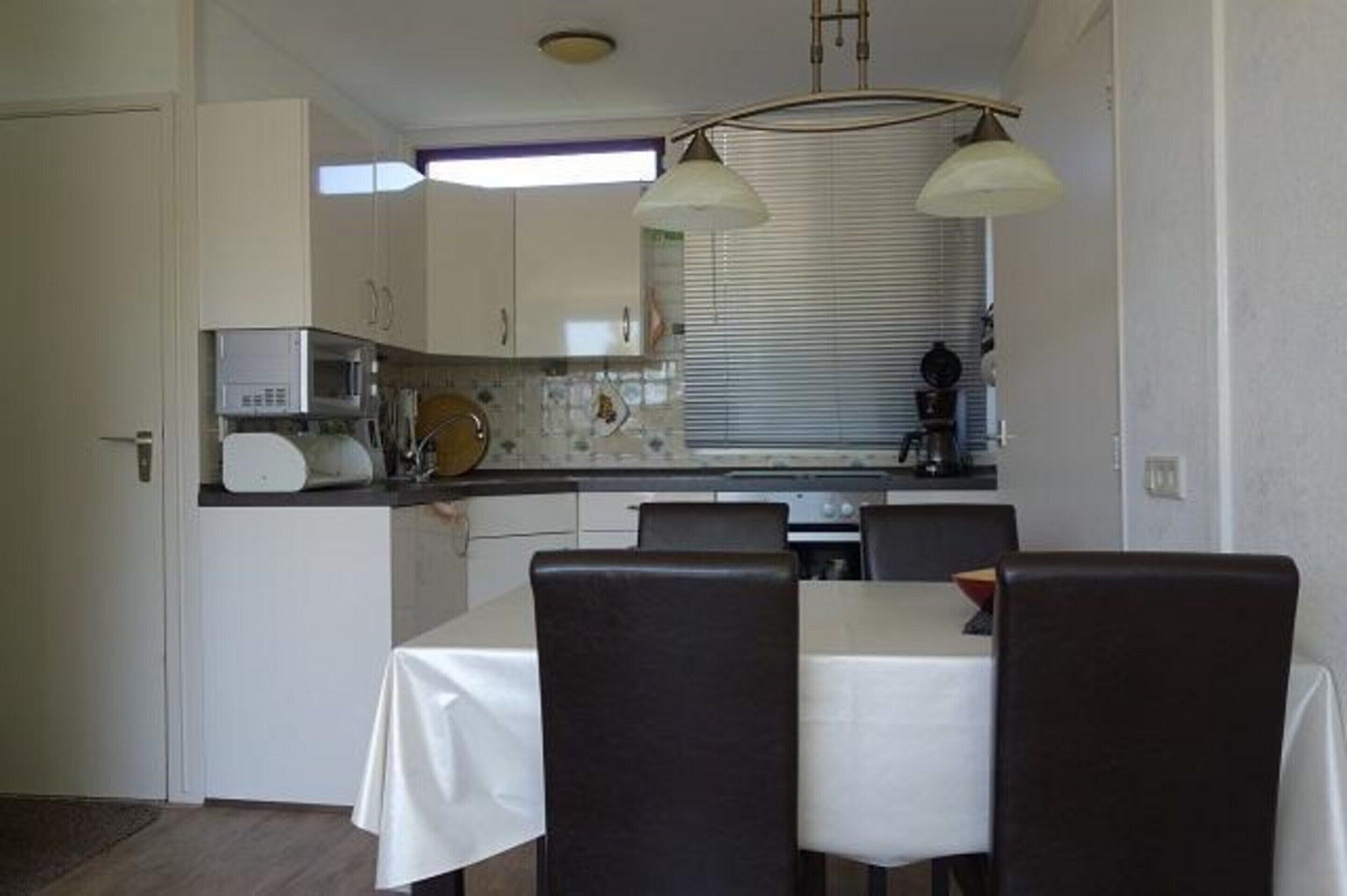 A compact kitchen with white cabinets, a microwave, and a dining area with a table and chairs.