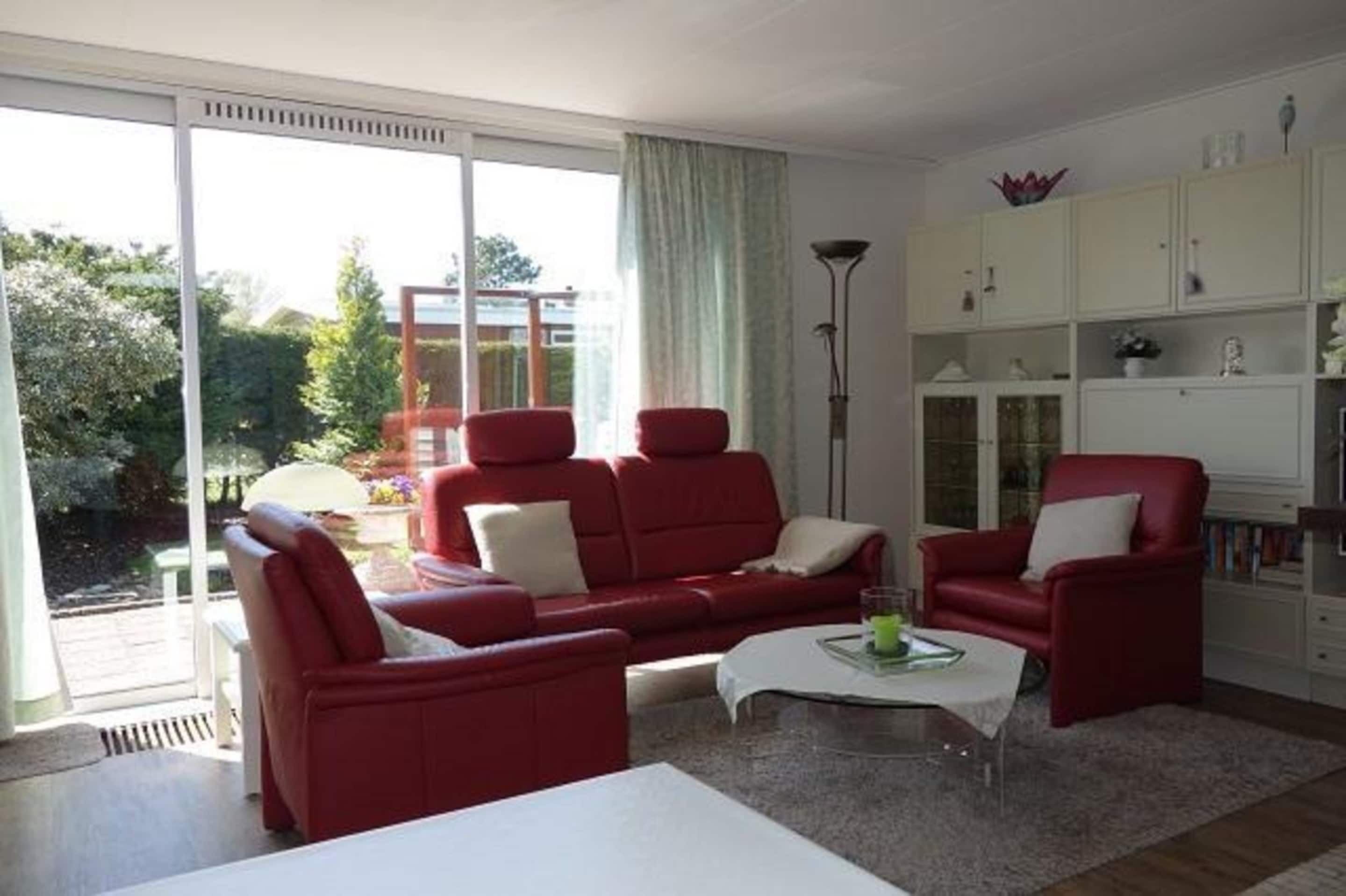 Ein Wohnzimmer mit einem roten Sofagarnitur, einem Couchtisch und einem Bücherregal.