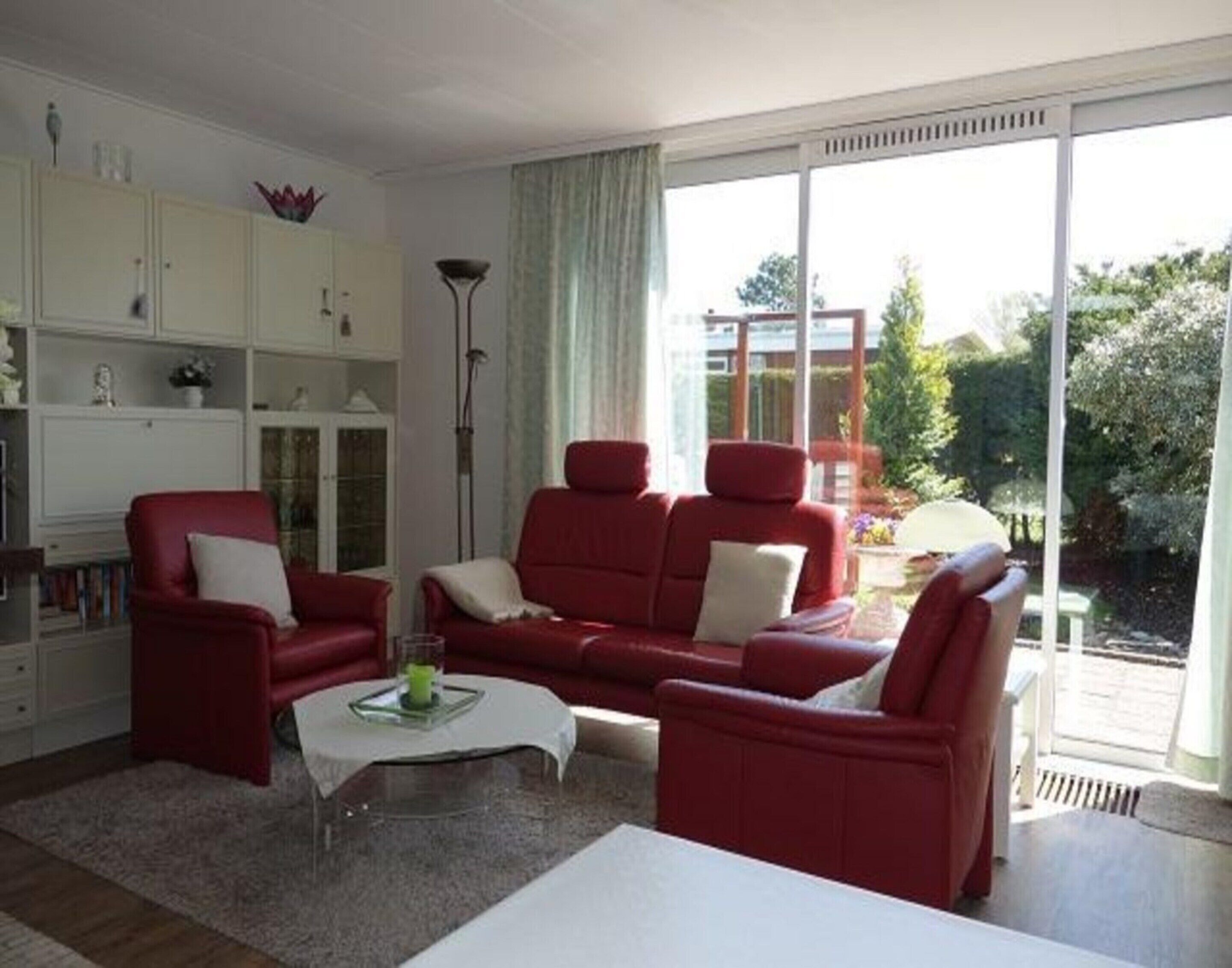 A living room with a red sofa set, a white coffee table, and a bookshelf.