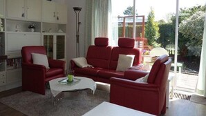 A living room with a red sofa set, a white coffee table, and a bookshelf. - Family Bungalow Near the Beach and sea (Sint Maartensvlotbrug)