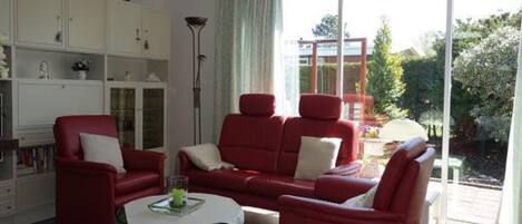 A living room with a red sofa set, a white coffee table, and a bookshelf.