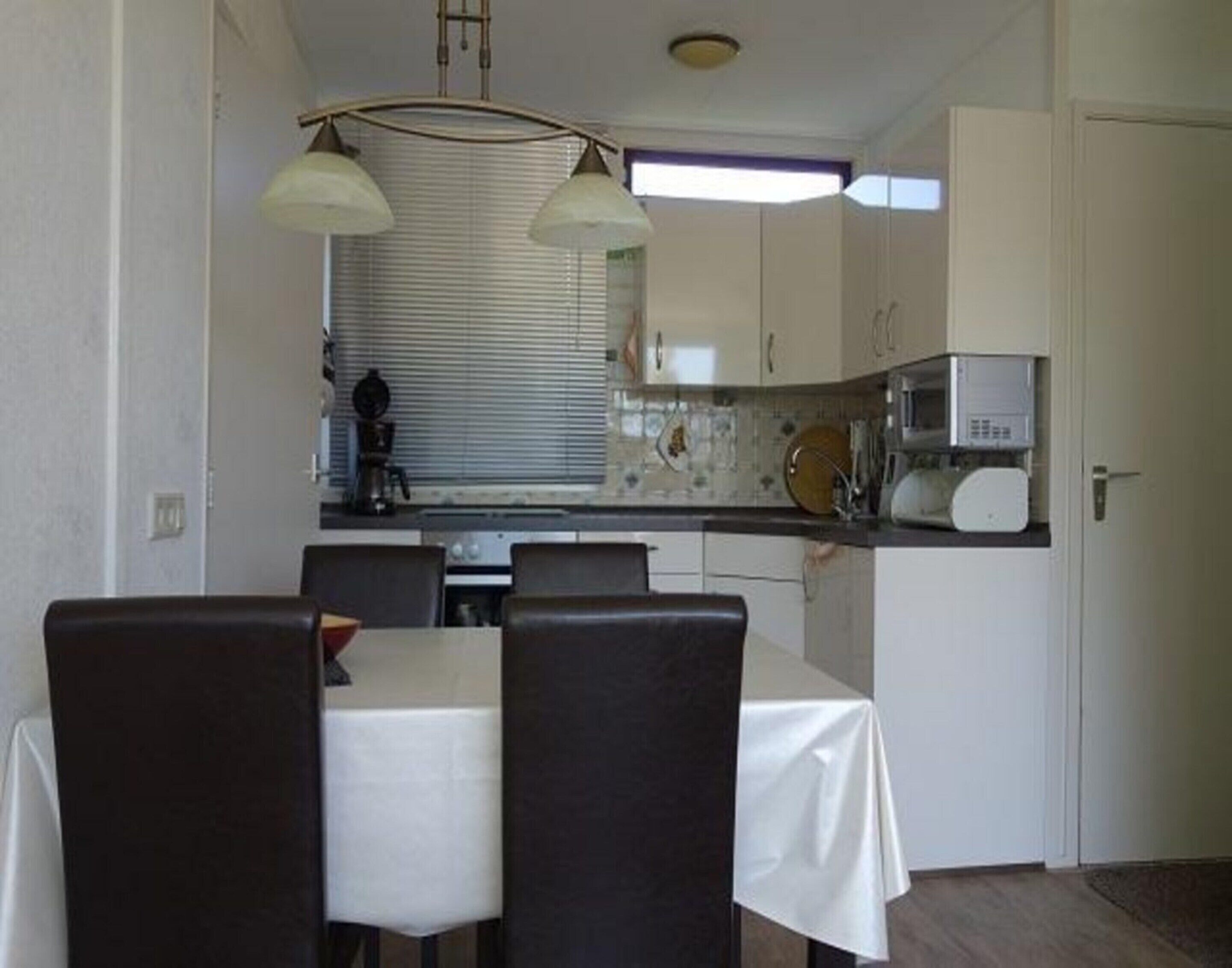 A compact kitchen with a dining table and chairs, a coffee machine, and a microwave.