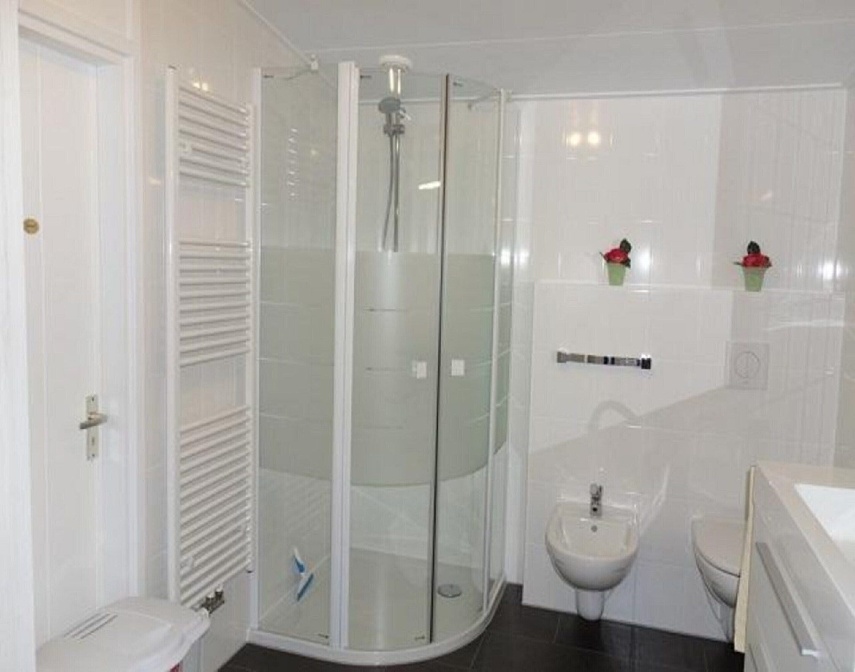 A modern bathroom with a glass-enclosed shower, a sink, and a toilet.