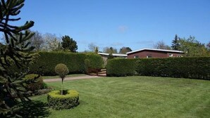 A well-maintained lawn with a neatly trimmed hedge and a small tree. - Family Bungalow Near the Beach and sea (Sint Maartensvlotbrug)