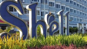 A large sign with the word "Shell" in bold letters, set against a backdrop of a multi-story residential building. - Shell Residences by Staycation (Pasay)