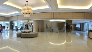 A spacious lobby with a large chandelier, a reception desk, and a seating area. - Shell Residences by Staycation (Pasay)