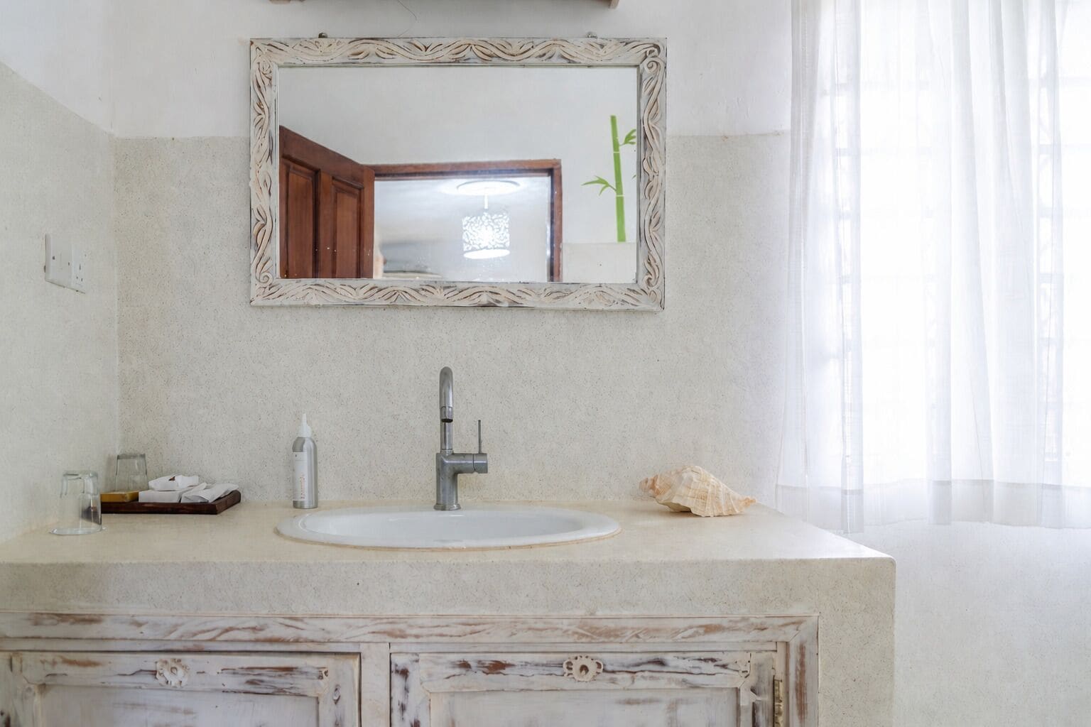 A bathroom with a white sink, a mirror, and a decorative cabinet.
