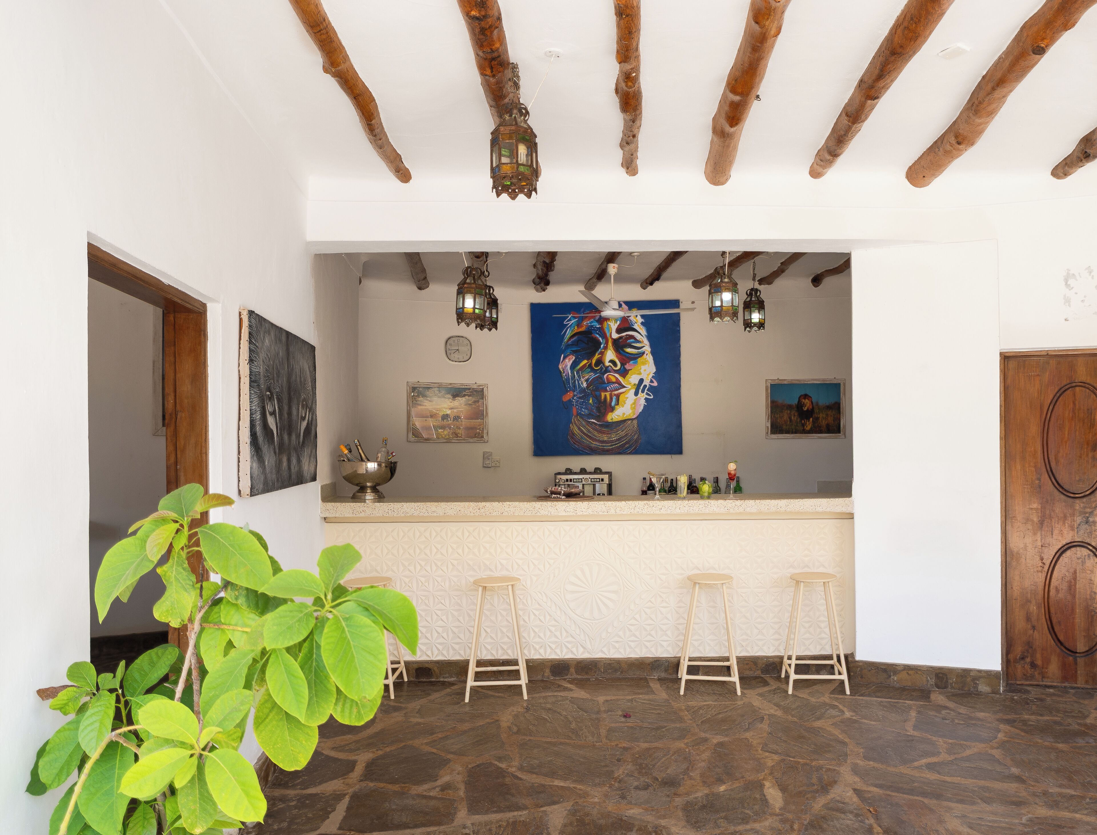 Una zona de bar con suelo de piedra, vigas de madera y un cuadro grande en la pared.