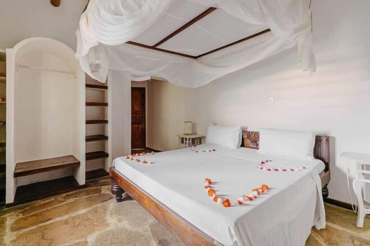 Un dormitorio con cama con dosel, una escalera y una silla blanca.