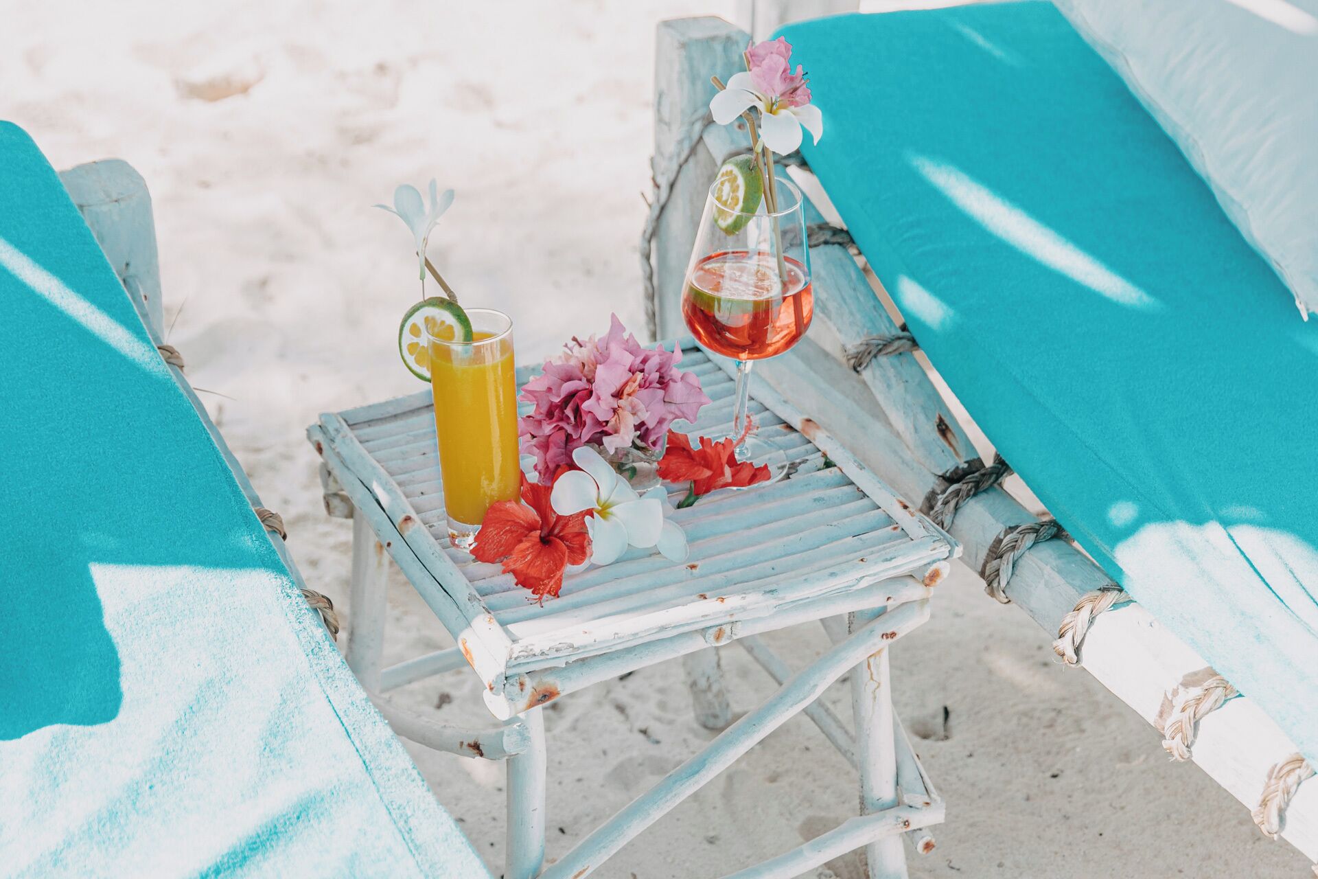 Una silla de playa con una bebida y flores.