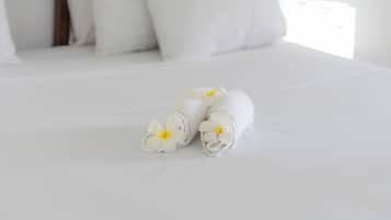 Una cama bien hecha con sábanas blancas y un par de toallas con flores amarillas.