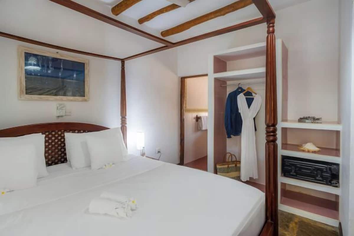 Una habitación de hotel con una cama grande, un armario, un espejo y un cuadro en la pared.
