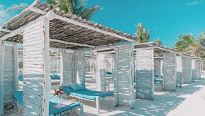A beach with multiple wooden cabanas, each with a blue cushioned bench and a small table. - Exploreans Beach Club & Villas Watamu (Malindi)