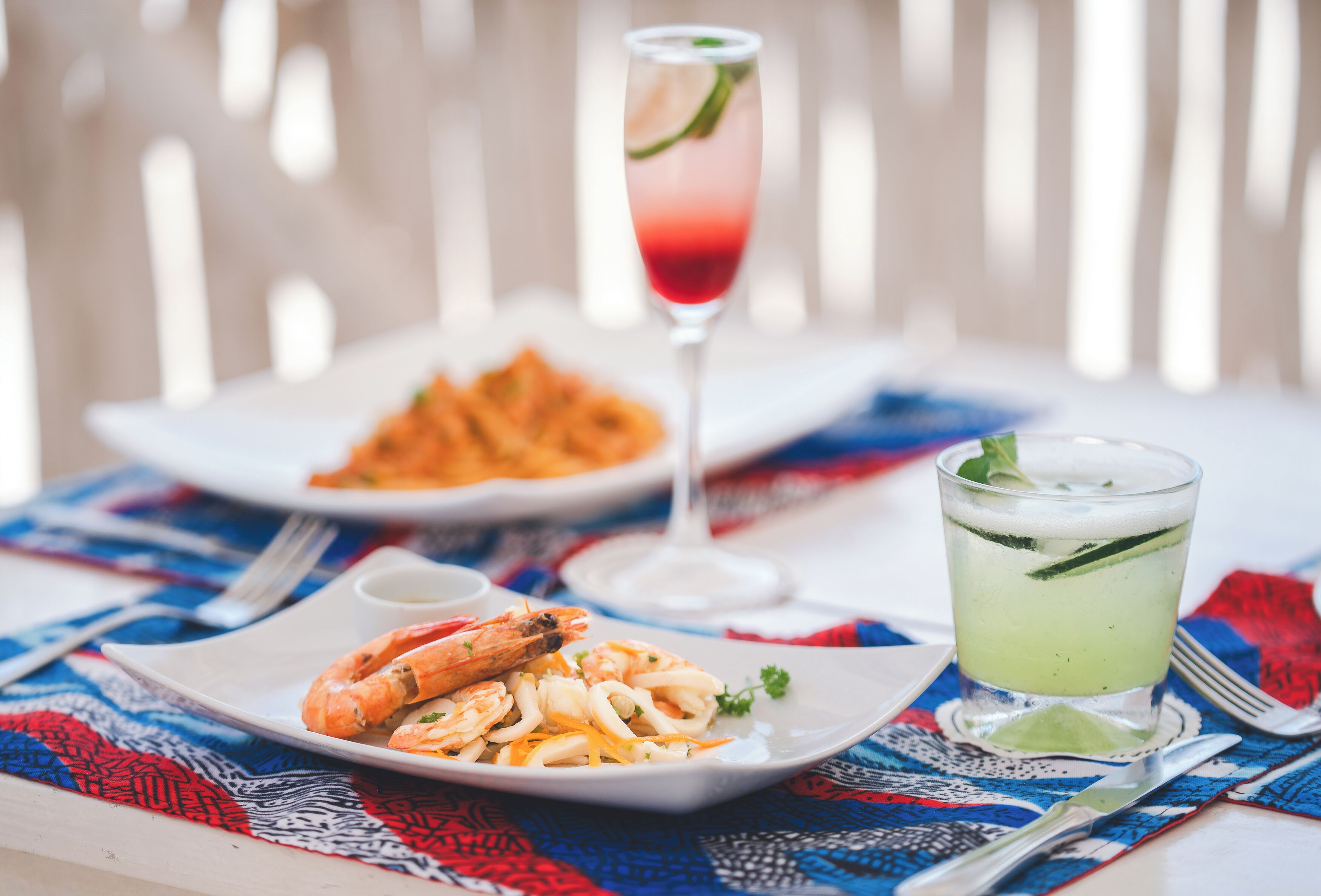 A dining table with seafood dishes and a cocktail.