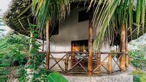 A rustic thatched-roof structure with a stone base, surrounded by lush greenery. - Exploreans Beach Club & Villas Watamu (Malindi)