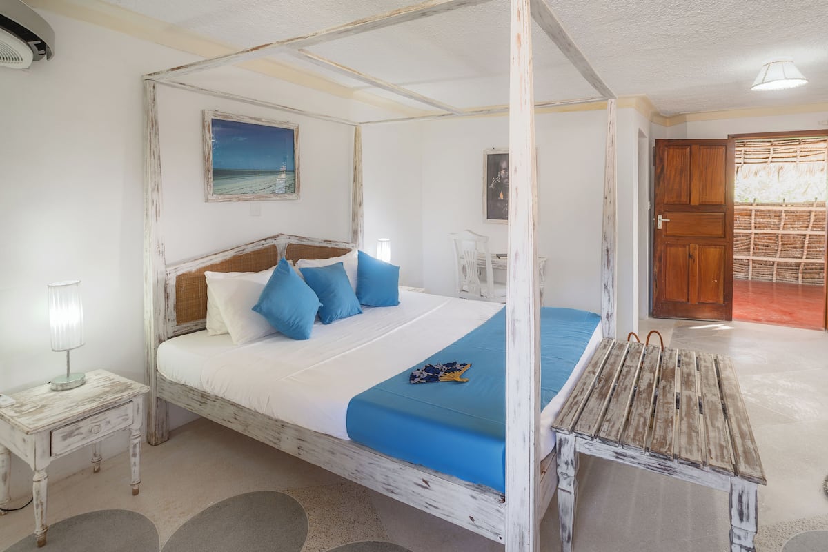 Una habitación con una cama con dosel, una mesita, una lámpara y un cuadro en la pared.