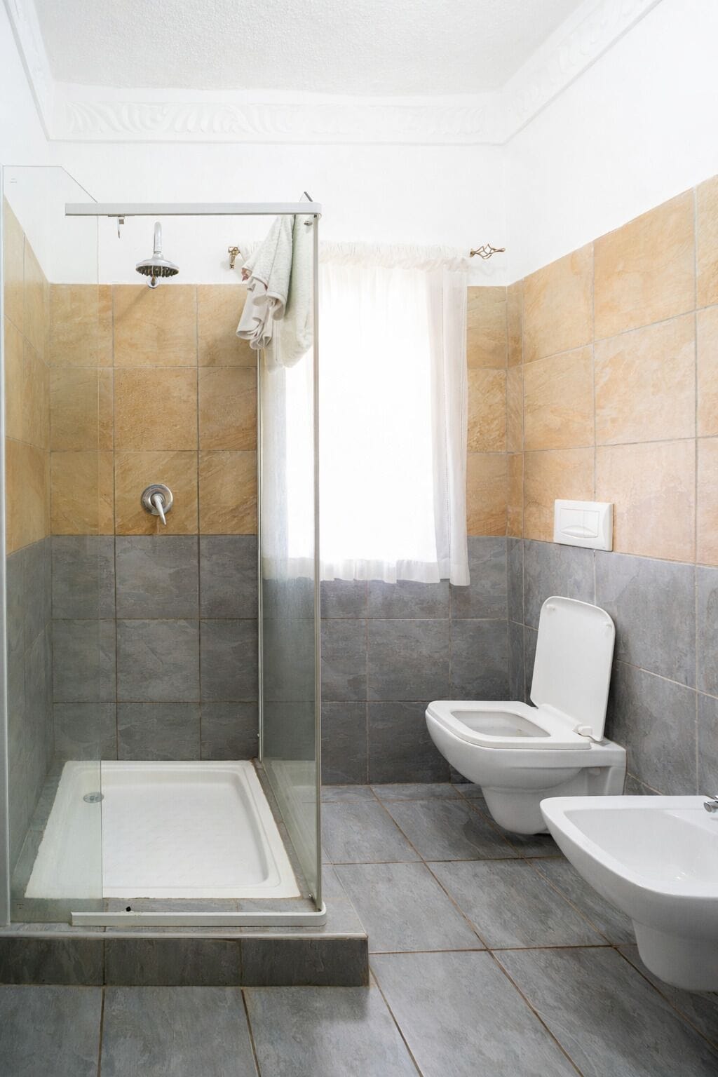 A modern bathroom with a glass-enclosed shower, a toilet, and a bidet.