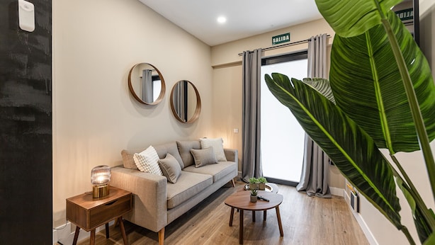 Una sala de estar moderna con un sofá, una mesa de centro y dos espejos en la pared.