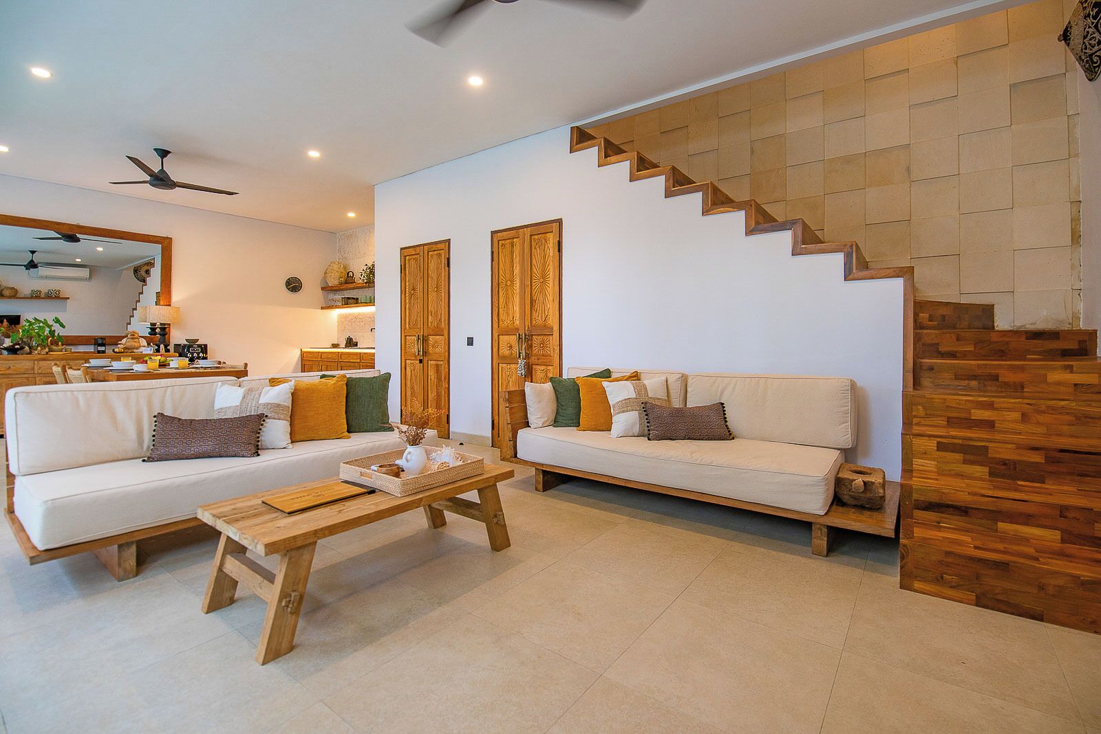 A modern living room with two sofas, a wooden coffee table, and a staircase with wooden steps.