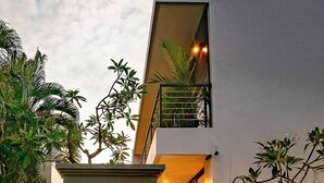 Ένα σύγχρονο κτίριο με μπαλκόνι, σκάλα και μια είσοδο που φωτίζεται καλά.
