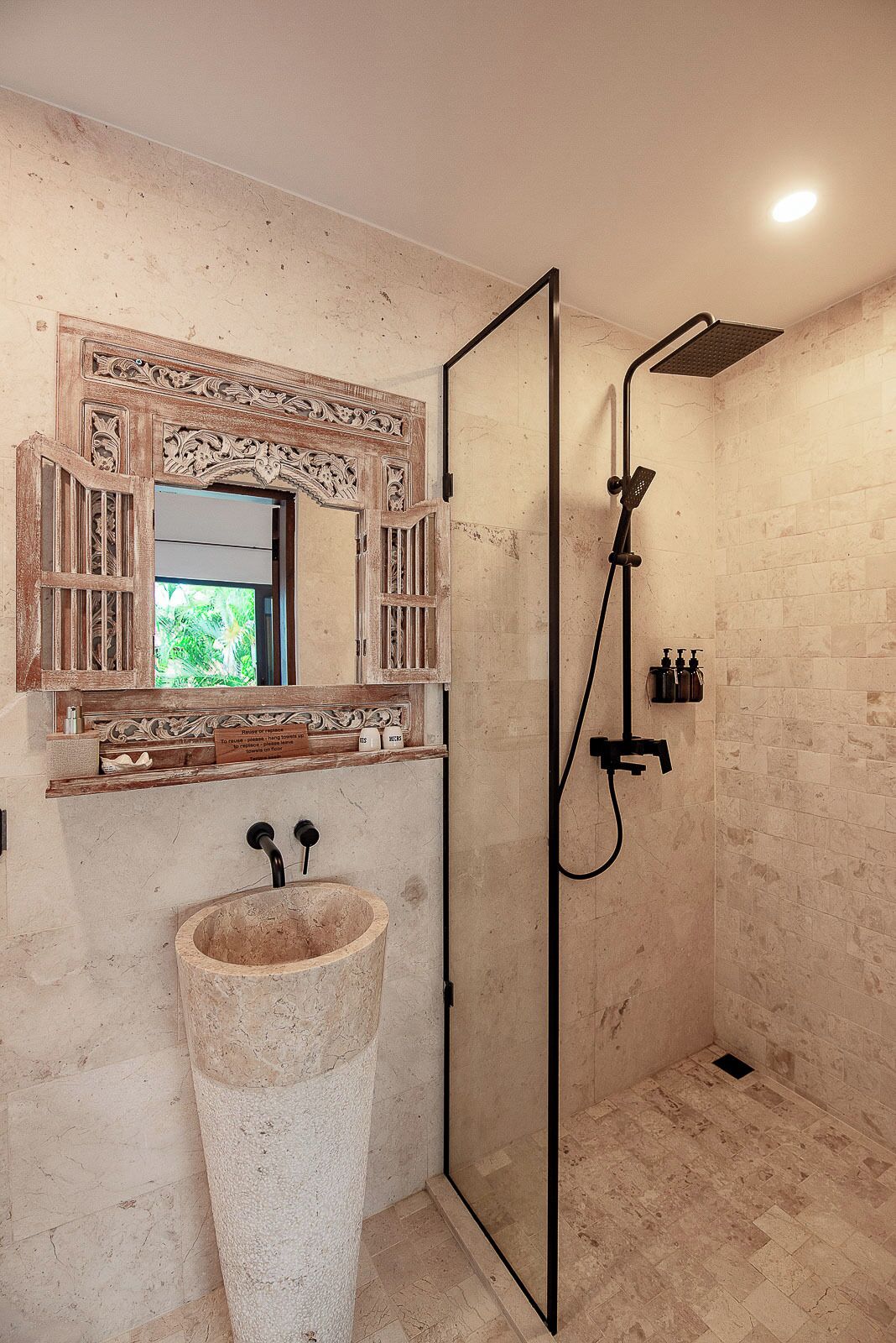 A bathroom with a large sink, a shower enclosure, and a decorative mirror.