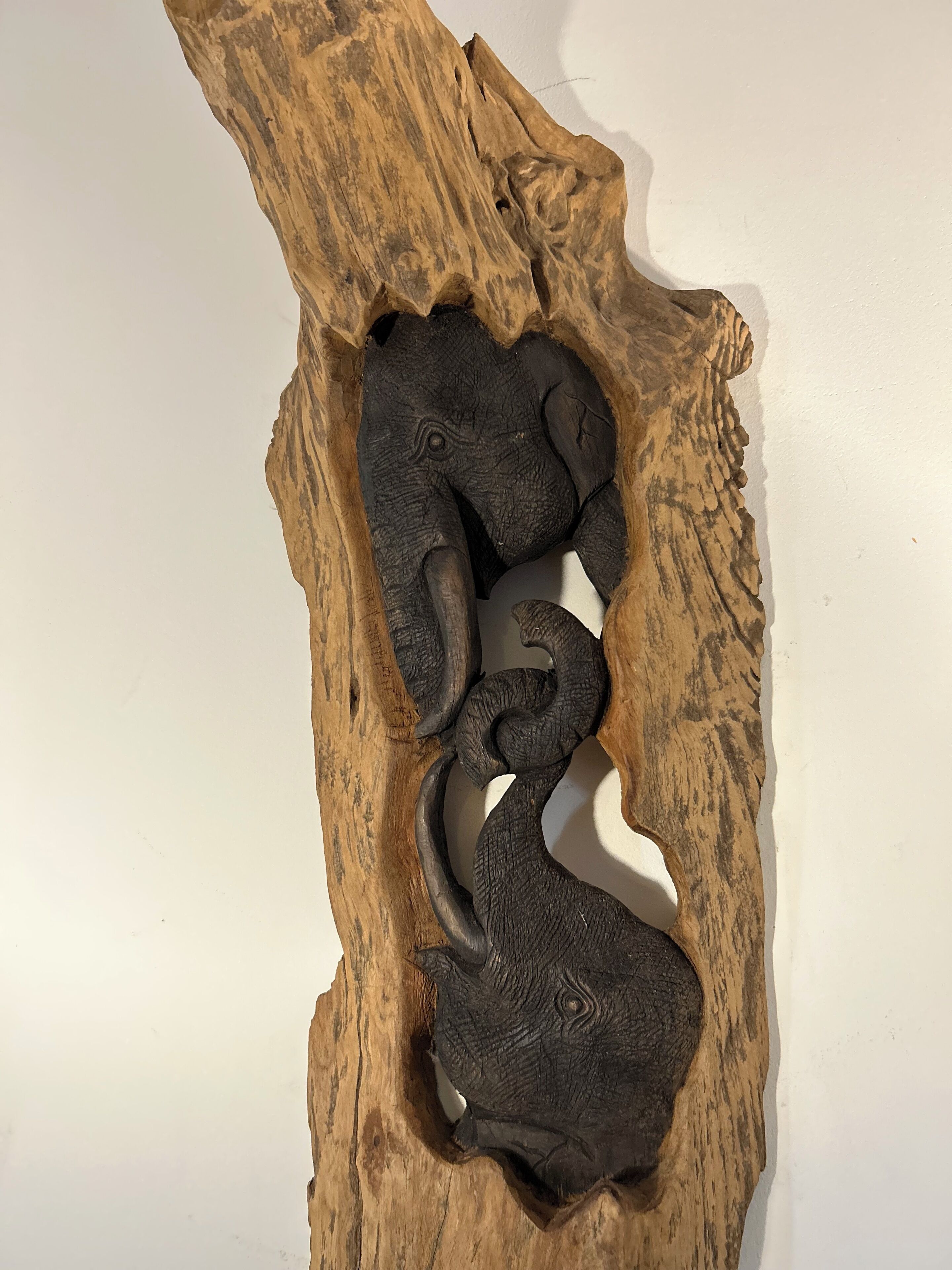 Una scultura in legno raffigura un elefante e un serpente intagliati.