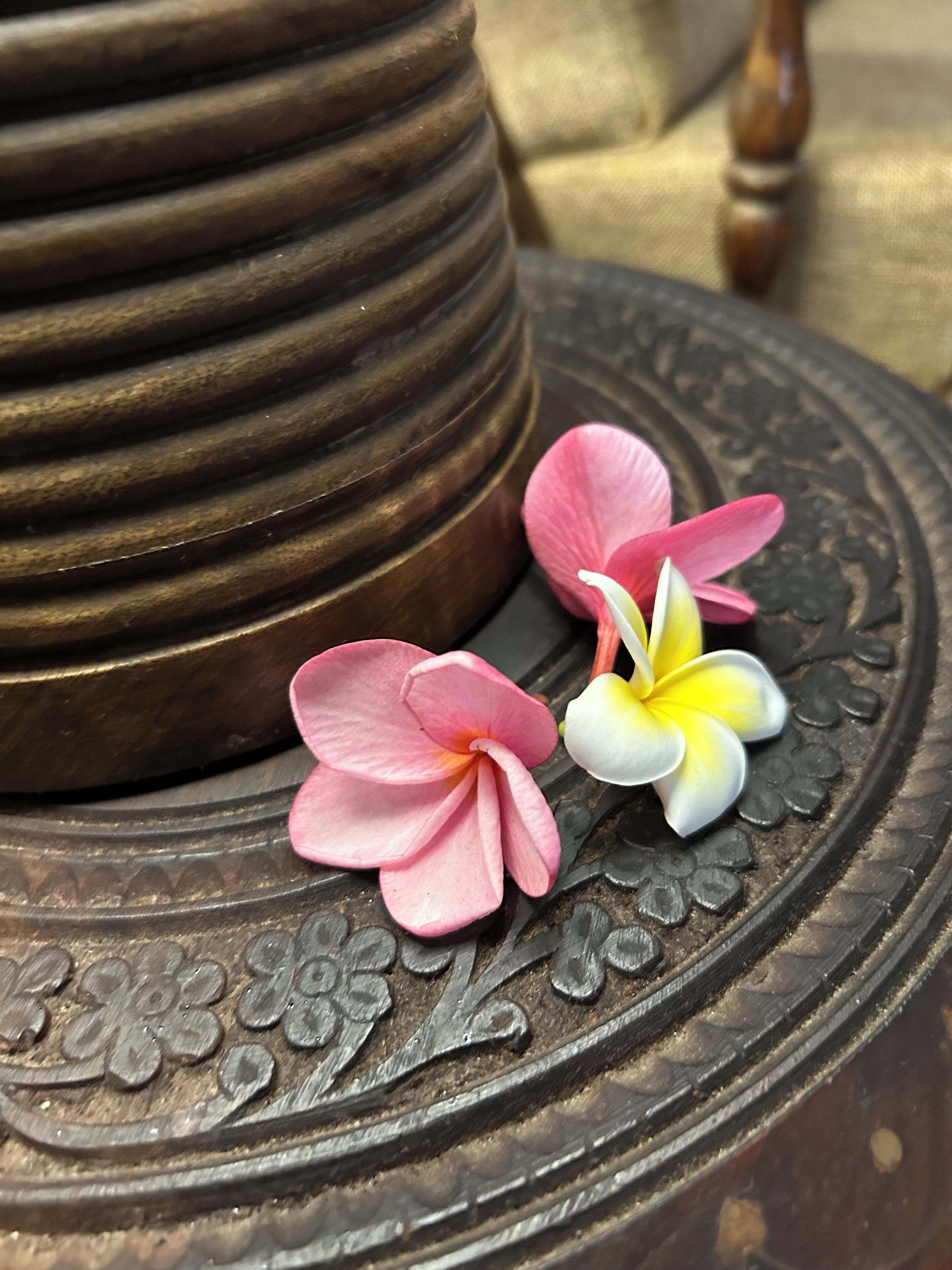 Un objeto decorativo de metal con diseños intrincados y dos flores sobre él.
