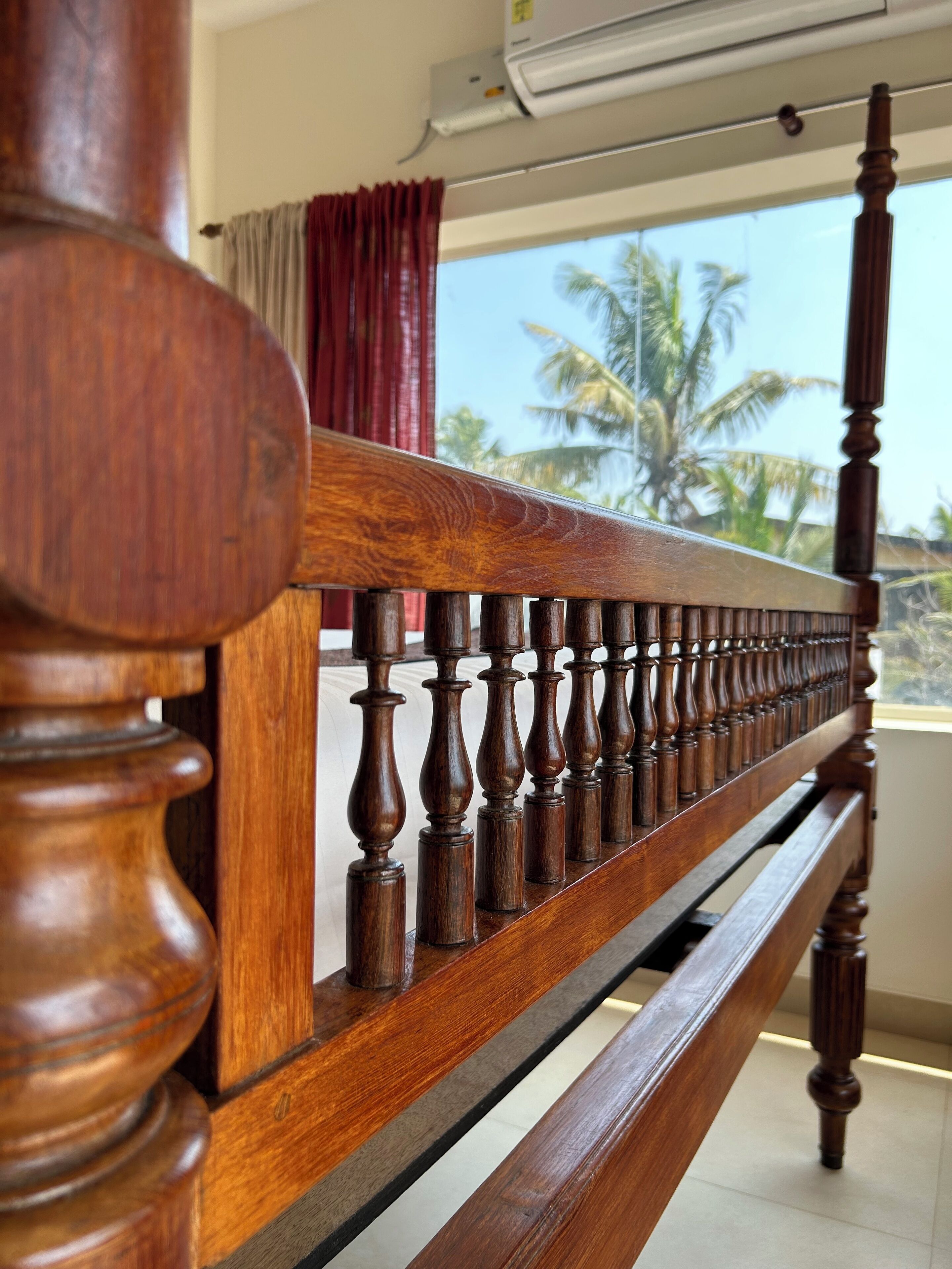 A wooden balcony railing with a view of palm trees and a clear sky.