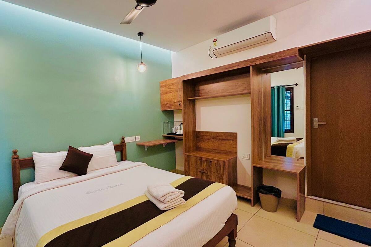 A neatly arranged bedroom with a bed, bedside tables, a wardrobe, and a mirror.