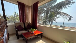 A balcony with a sofa, a wooden coffee table, and a potted plant.