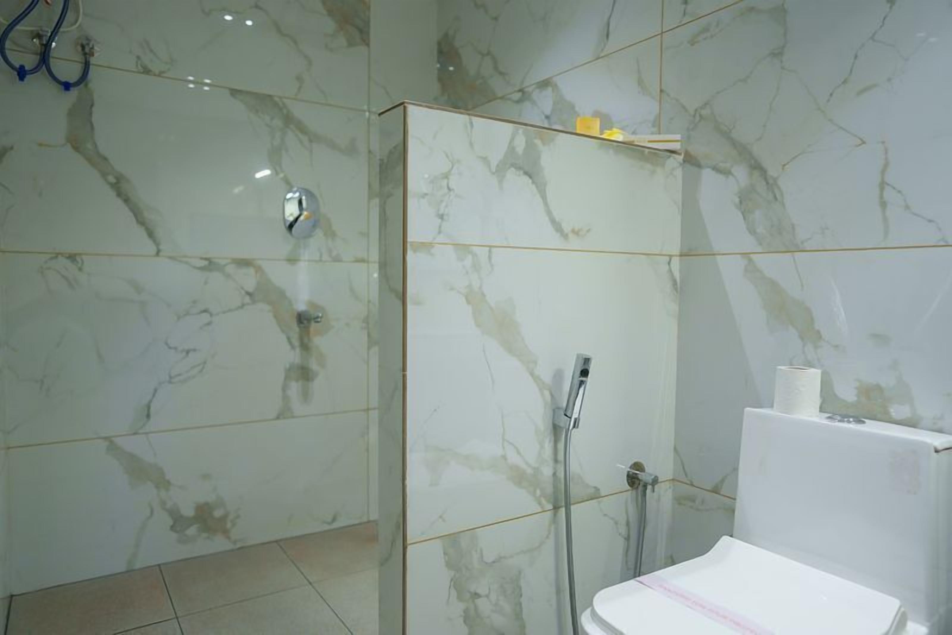 Bagno con pareti in marmo, doccia e water.