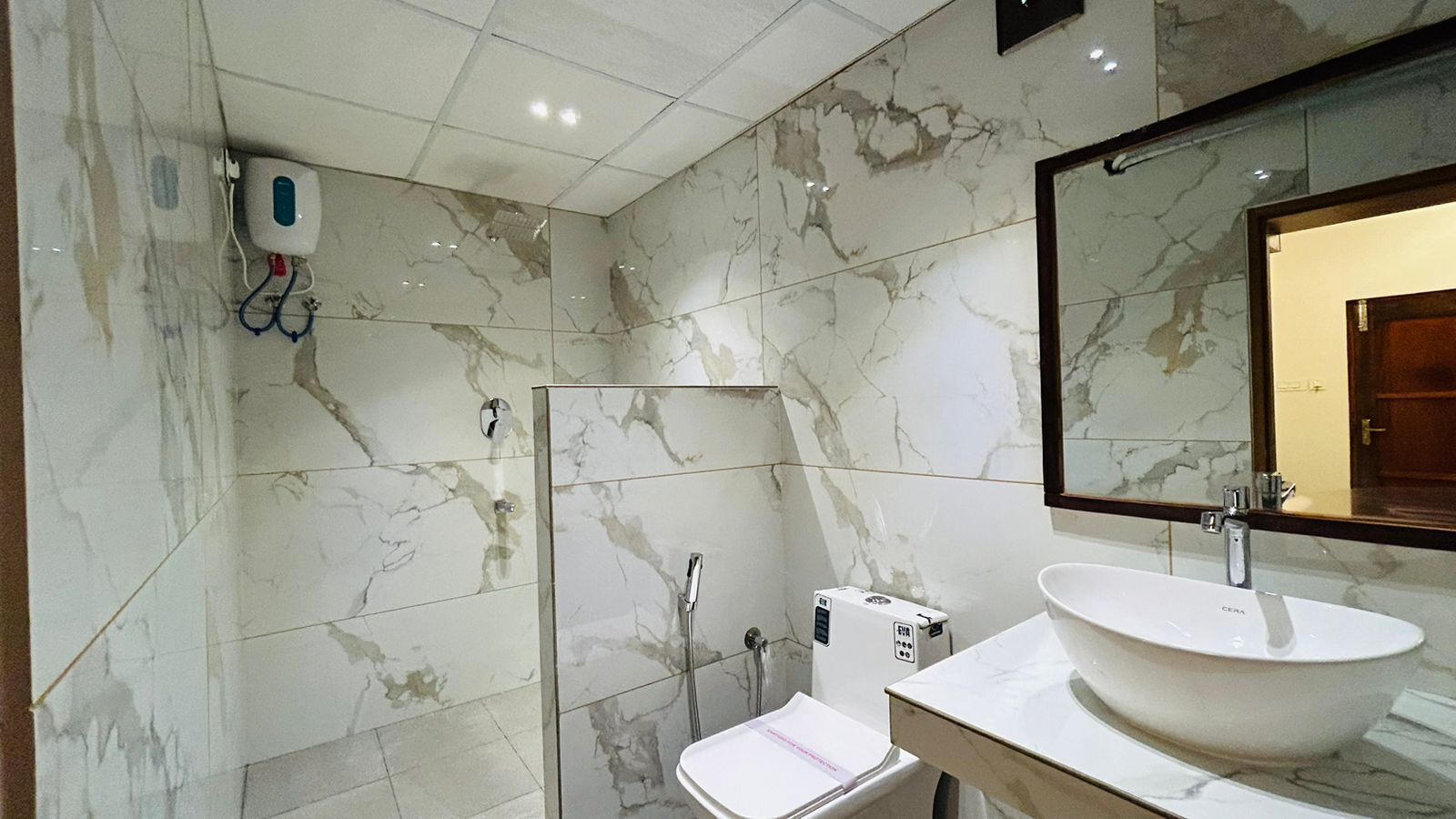 A bathroom with a marble floor, a large mirror, a sink, and a shower.