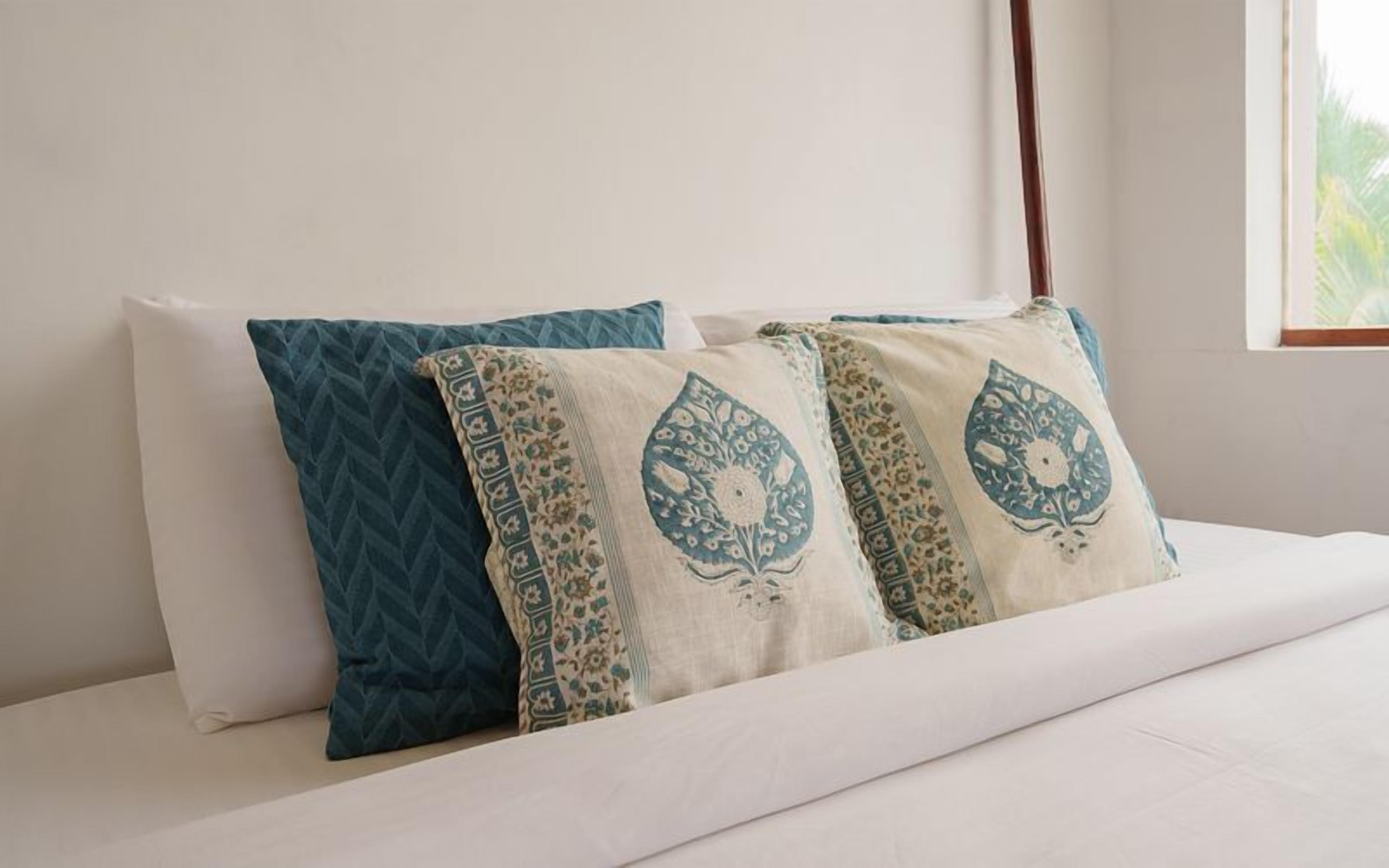 A bed with two pillows, one with a geometric pattern and the other with a floral design.