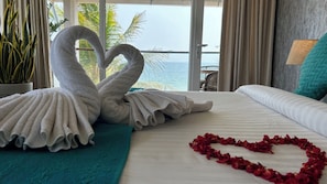 A hotel room with a bed, a heart-shaped arrangement of rose petals, and two towels shaped like swans. - Santa Maria - A Premium Boutique Homestay by the Sea (Thiruvananthapuram)