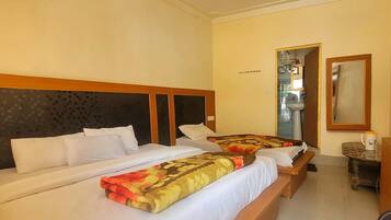 A double bed with a patterned blanket, a bedside table with a cup, and a ceiling fan.