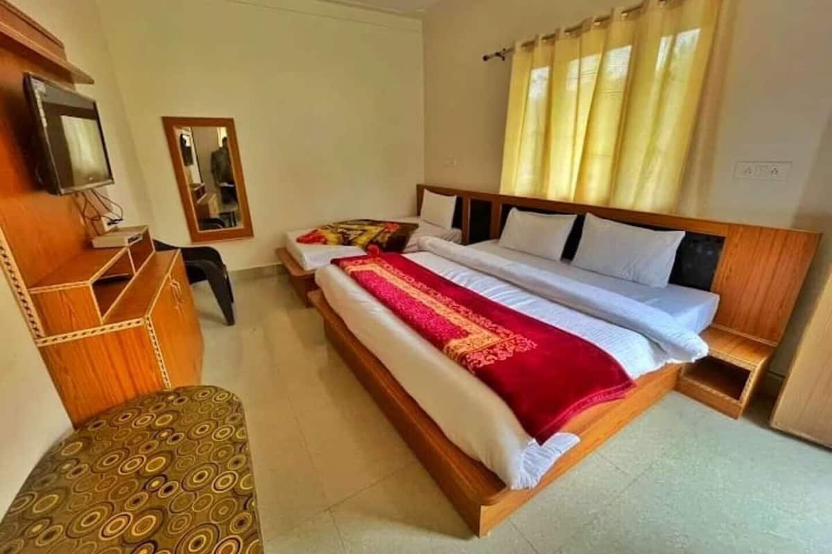 Ein Hotelzimmer mit einem großen Bett, einem Holztisch, einem Stuhl und einem Fernseher.