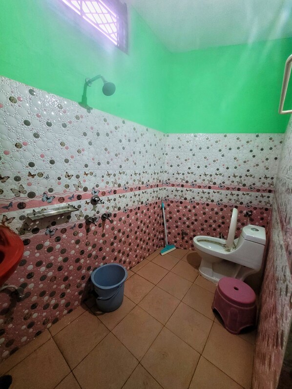 A small bathroom with a toilet, bidet, and a bucket. The walls are decorated with a polka dot pattern. - Shivlok Hotel  (Ukhimath)