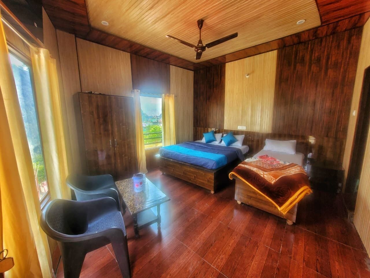 A bedroom with two beds, a ceiling fan, and a view of the outdoors.