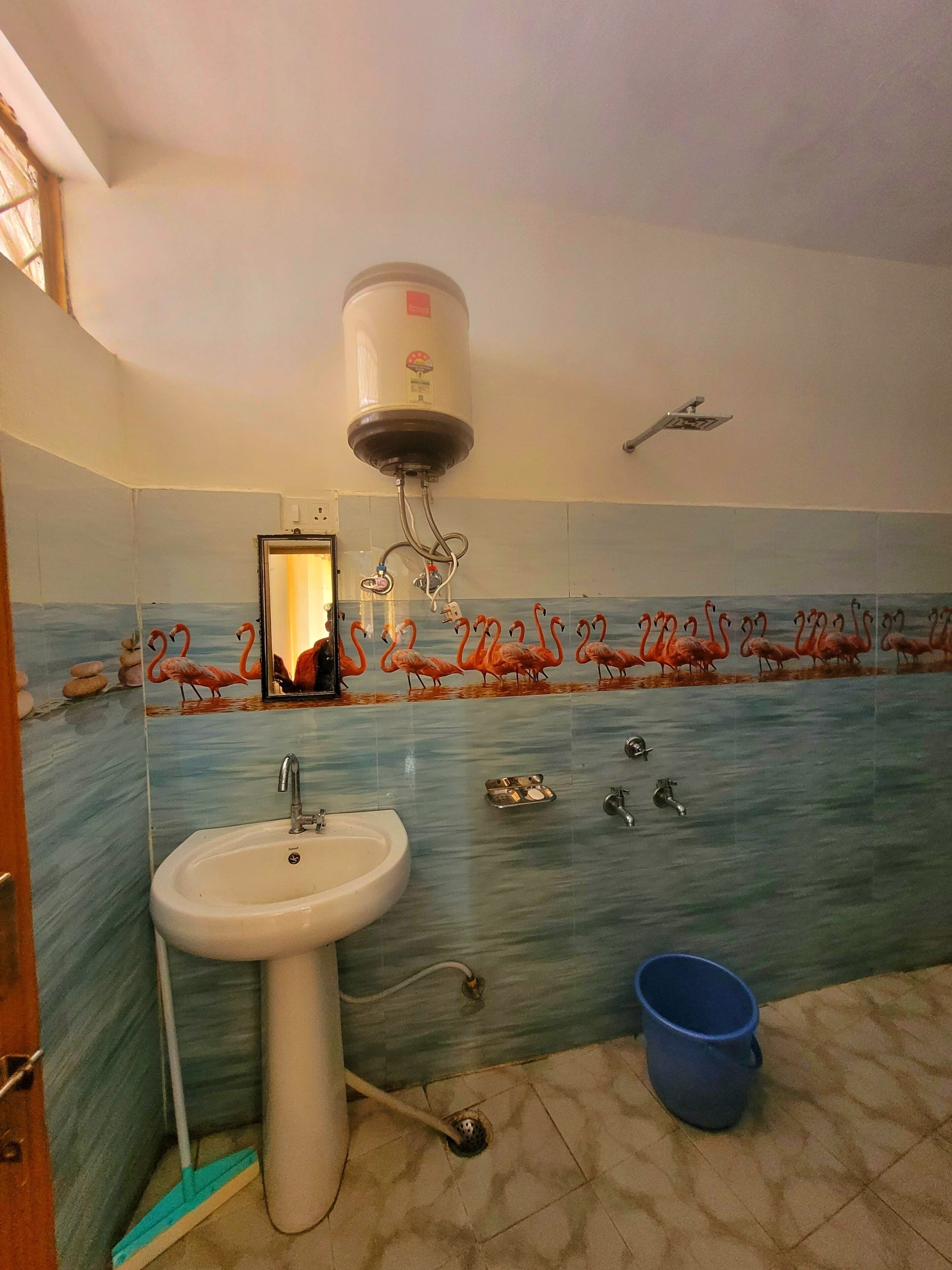 Een badkamer met een wastafel, spiegel en een muur met een flamingo dessin.