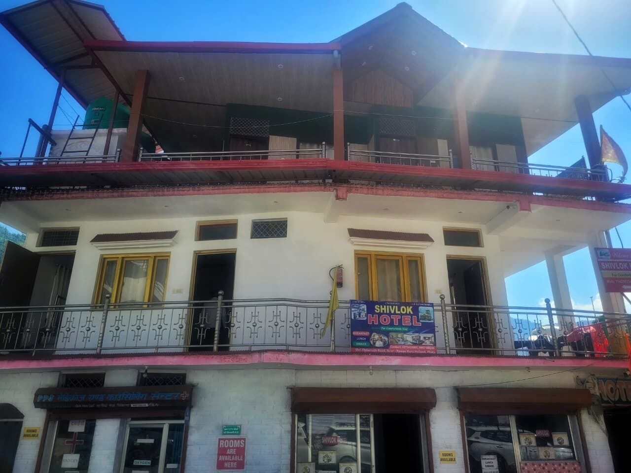 Un bâtiment à deux étages, avec une enseigne indiquant qu’il s’agit de l’hôtel Shivlok, des balcons et une autre enseigne signalant que des chambres sont disponibles.