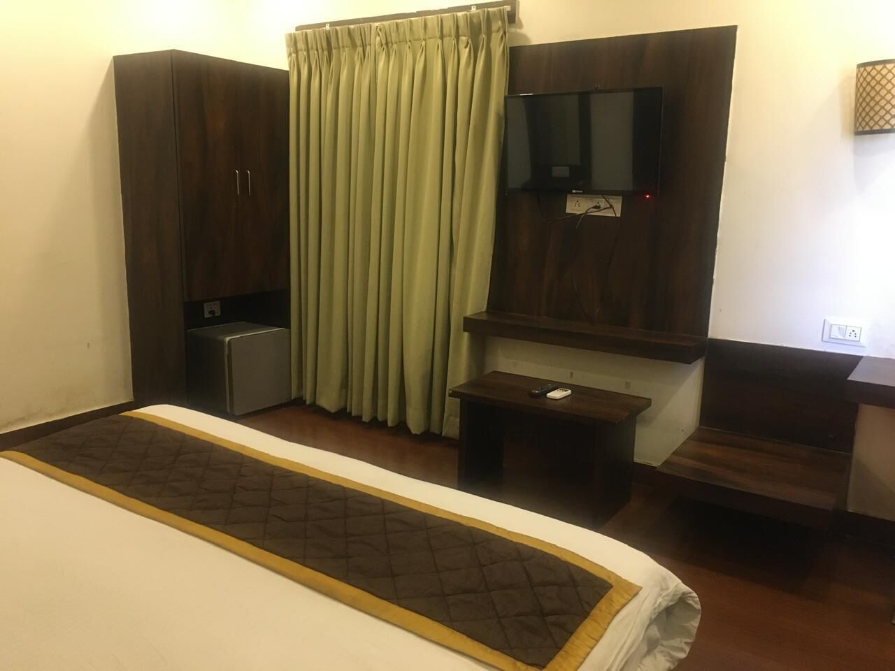 A hotel room with a bed, a desk, a TV, and a wardrobe.