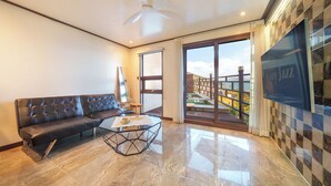 A modern living room with a leather sofa, a glass coffee table, and a large TV screen. - Geoje Piscina Pool Villa (Geoje)