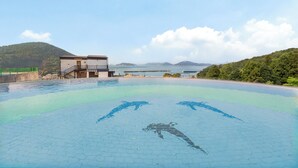 A swimming pool with a diving board and a building in the background. - Geoje Piscina Pool Villa (Geoje)